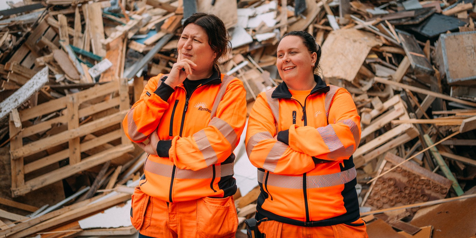 Två medarbetare står framför en hög med trä