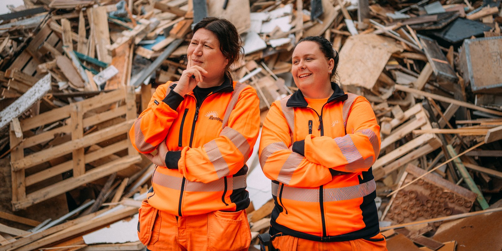 Två personer står framför trähög